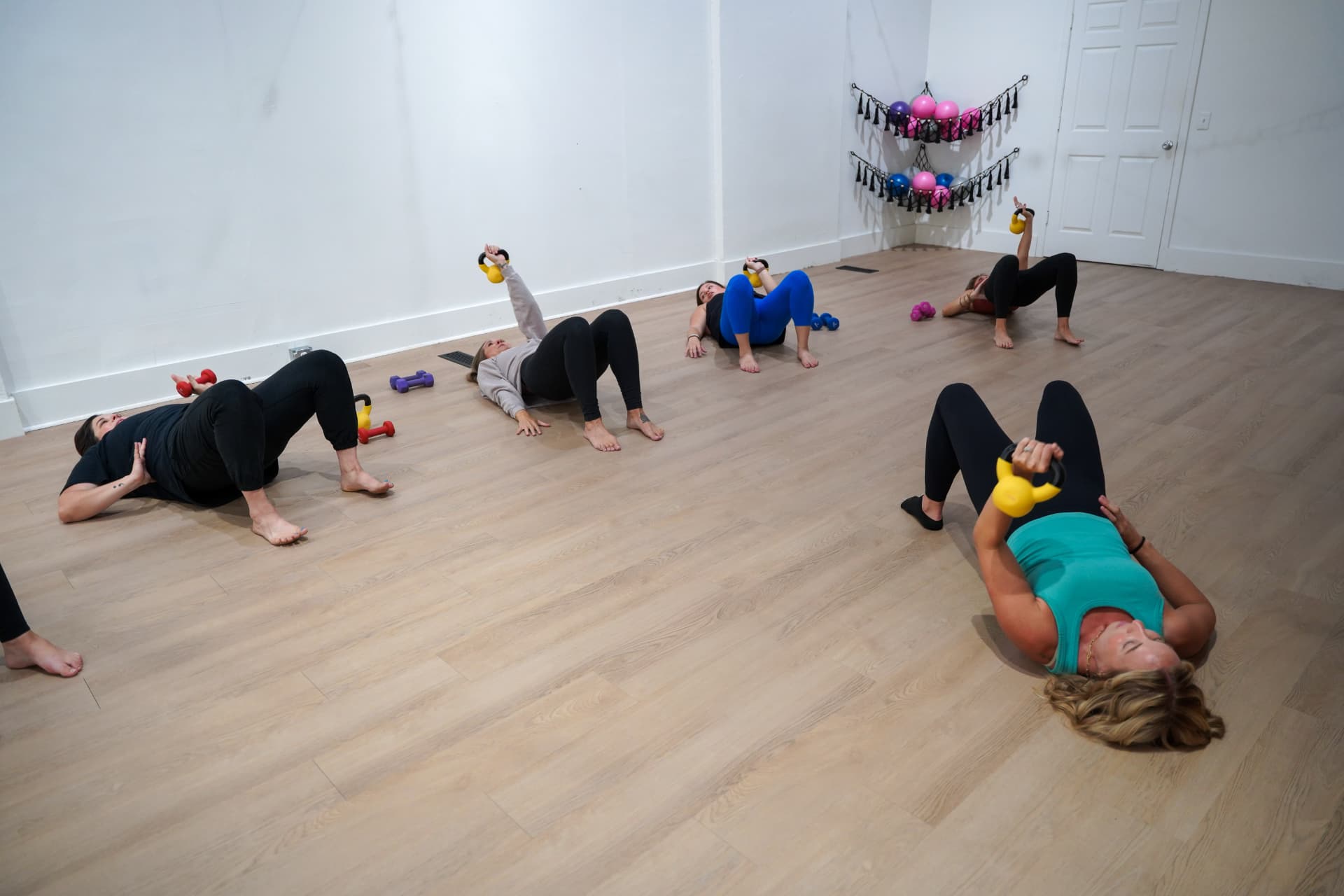 A small strength training group at Homegrown pressing kettlebells from the floor