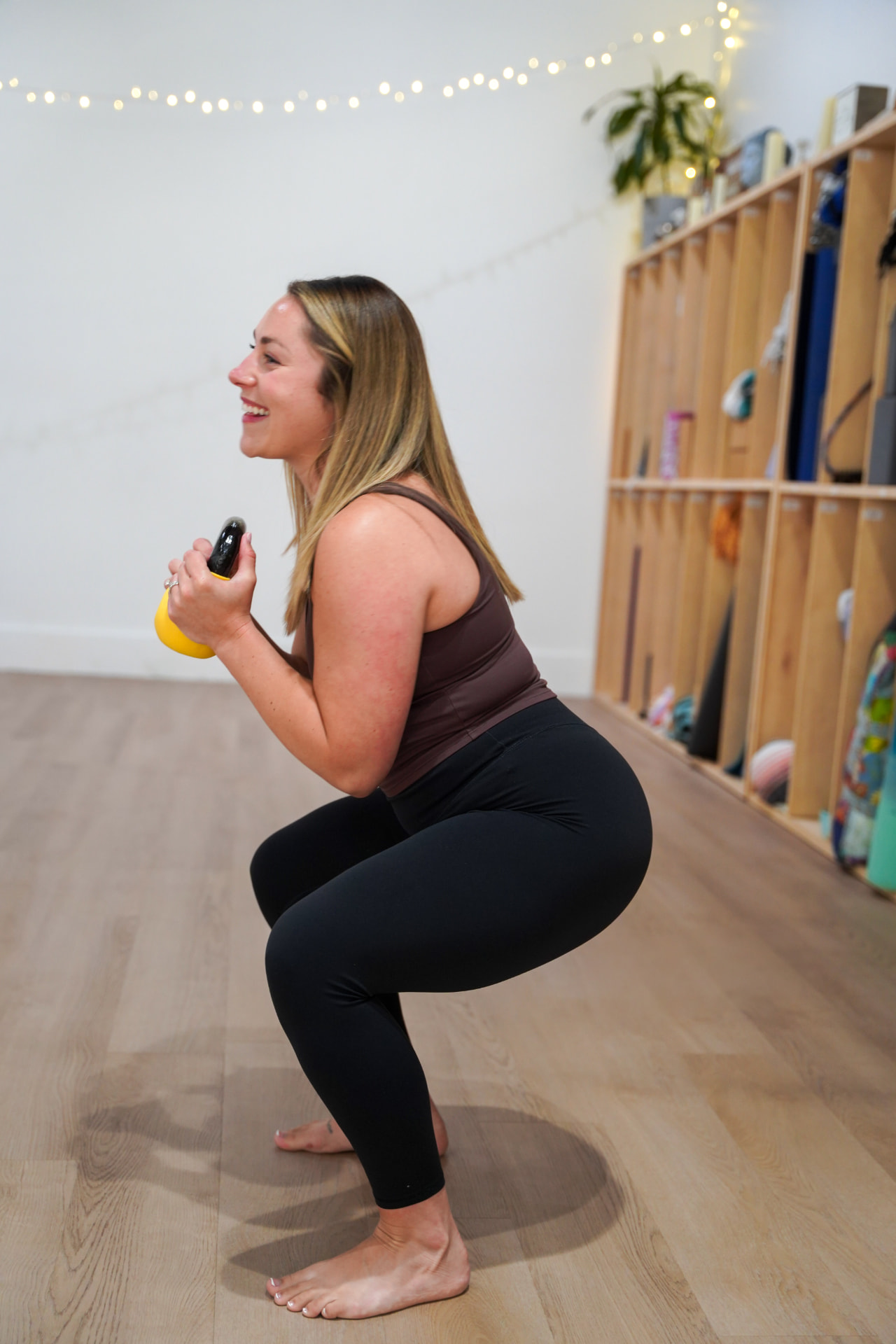 A member holding a kettlebell at her chest in a deep squat